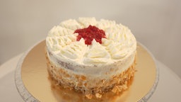 Die Kirsch-Mohn-Torte drapiert auf einer goldenen Unterlage