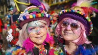 Zwei Frauen mit kunterbunten Kostümen, Sonnebrillen und Karnevalsschminke im Gesicht