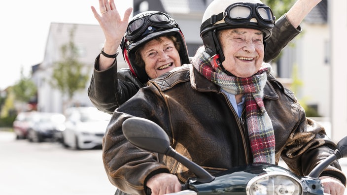 Zwei glückliche, ältere Menschen auf einem Motorad