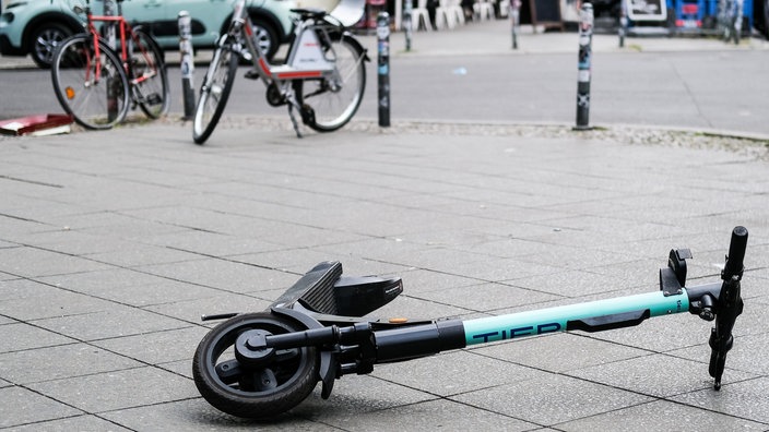 Ein E-Scooter liegt umgekippt auf einem Gehweg.