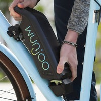 Ein Mann mit Radhelm hantiert an einem E-Bike Akku
