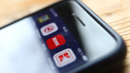 Icons der Apps von den Handelsketten Edeka (l-r), Rossmann, REWE und Kaufland sind auf dem Display eines iPhones zu sehen.