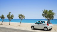 Das Bild zeigt einen Mietwagen auf einer Straße am Meer.