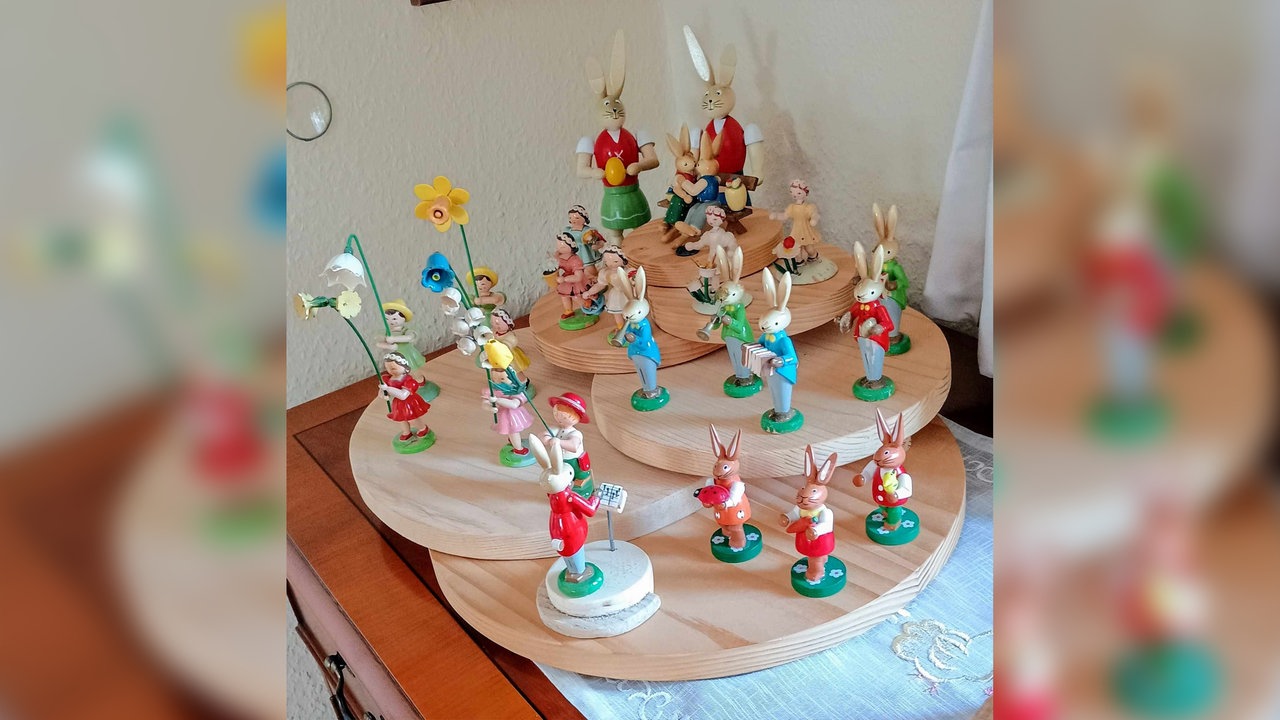 Mehrere kleine Osterhasen aus Holz stehen in einem Zimmer.