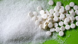 Süßstofftabletten liegen neben Hauhaltszucker
