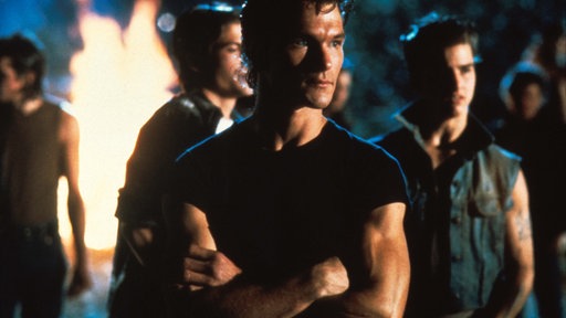 Darry (Patrick Swayze, Mitte) führt die „Greasers“, u.a. Sodapop (Rob Lowe, hinten) und Steve (Tom Cruise, r.), in den Kampf gegen die „Socs“.