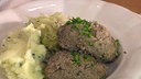 Zwei Leberknödel mit Beilagen auf einem Teller angerichtet
