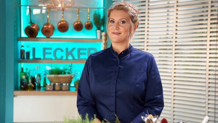 Julia Komp in der Küche mit Kräuternin der Hand.
