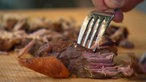 Pulled-Pork-Fleisch wird mit einer Gabel zerrupft. 