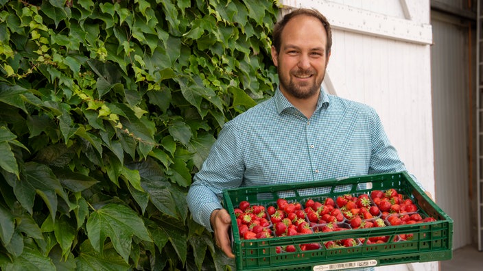 Benedikt Böcker mit einer Kiste Himbeeren. 