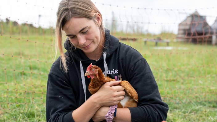 Marie Owens mit einem Huhn auf dem Arm.