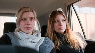 Zwei junge Frauen sitzen in einem Auto.
