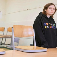 Ein Mädchen steht in einem leerem Klassenraum mit betrübten Blick.