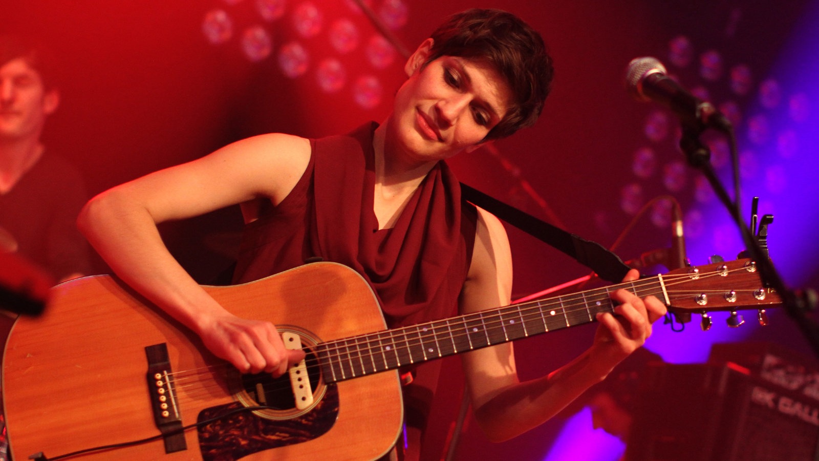 Alin Coen spielt Gitarre und schaut dabei lächelnd nach unten