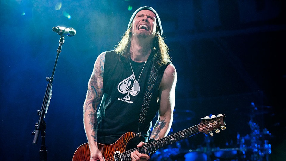 Bandmitglied von Alter Bridge spielt Gitarre und singt dabei mit schmerzverzerrtem Gesicht