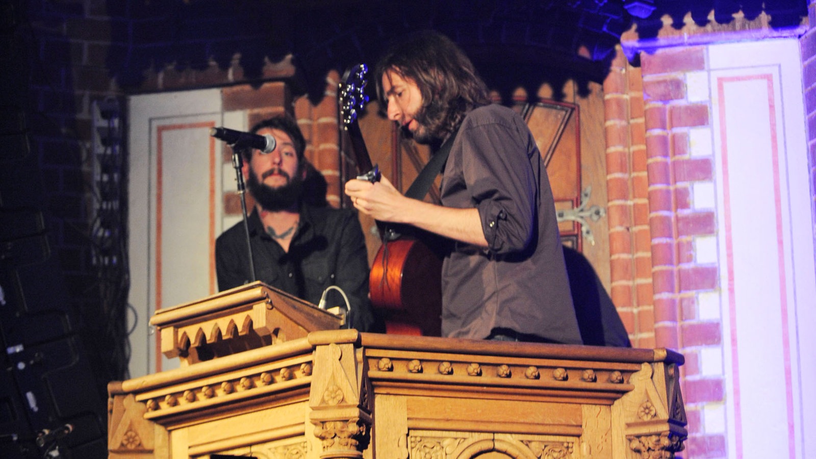 Sänger und Gitarrist stehen auf einer Kanzel und spielen 
