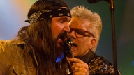 Mundharmonikaspieler und Sänger der Band Big Sugar singen zusammen ins Mundharmonikamikrofon, es wirkt fast so als würden sie sich küssen, sehr romantisch