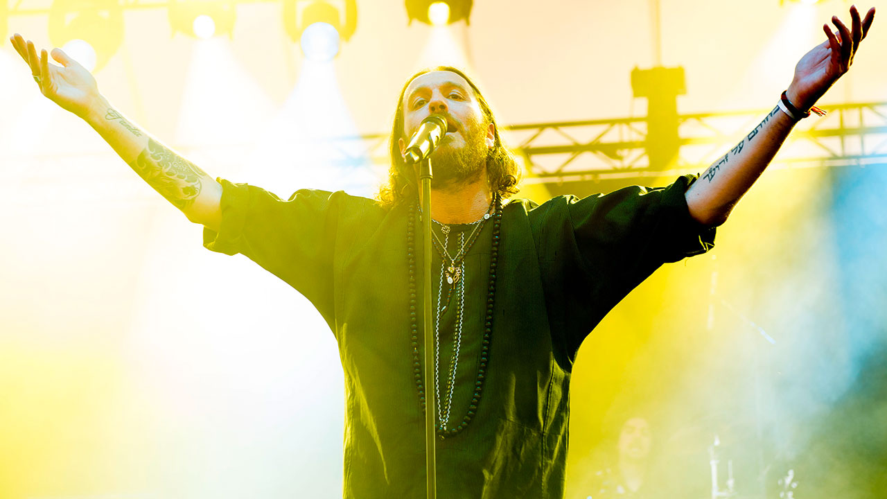 Der Sänger von Orphaned Land am Mikro vor einem strahlend gelben Licht