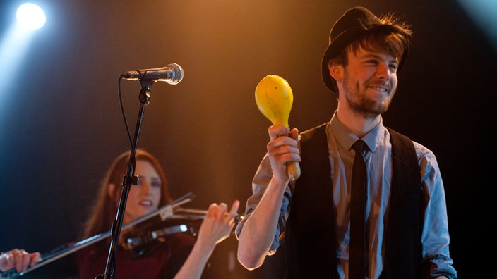 Hintergrundmusiker von Blaudzun, eine Streicherin und ein Percussionist mit einem Shaker.