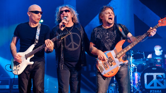Sänger, Gitarrist und Bassist von Chickenfoot stehen nebeneinander und musizieren zusammen