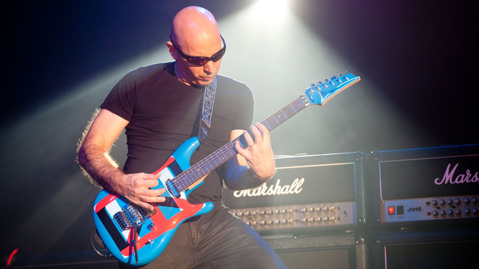 Joe Satriani beugt sich beim Spielen über seine Gitarre