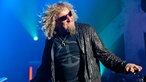 Sammy Hagar leicht nach rechts gebeugt und  den linken vom Körper weg gestreckt