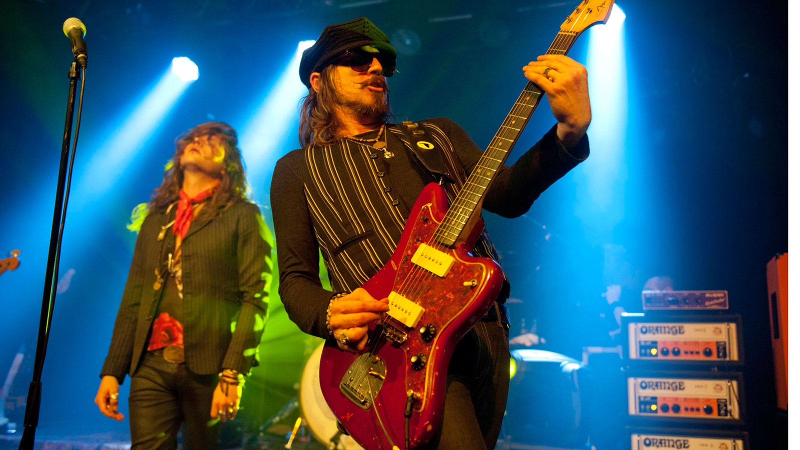 Gitarrist der "Rival Sons" spielt mit hochgehaltener Gitarre, im Hintergrund steht der Sänger und legt seinen Kopf nach hinten.
