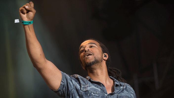 Dub Inc Frontman Aurélien regt seine Faust in die Luft.