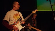 Zwei Männer mit Gitarren beim Soundcheck.