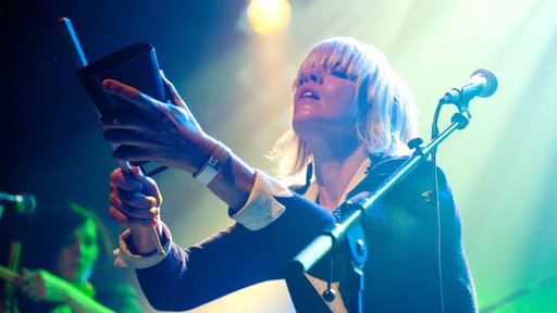Eine blonde Sängerin der Band Tu Fawning steht auf der Bühne