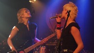 Die Bassistin und die Sängerin von AK4711 stehen sich bei Bootleg im April 2006 gegenüber und sehen sich an.
