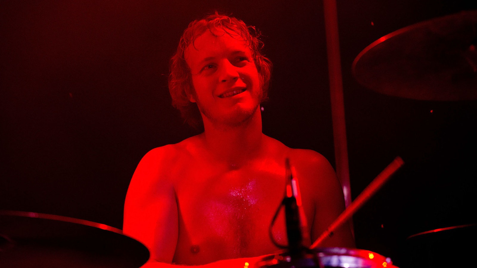Ein Portrait des in rotes Licht getauchten Schlagzeugers der Band Birth of Joy.