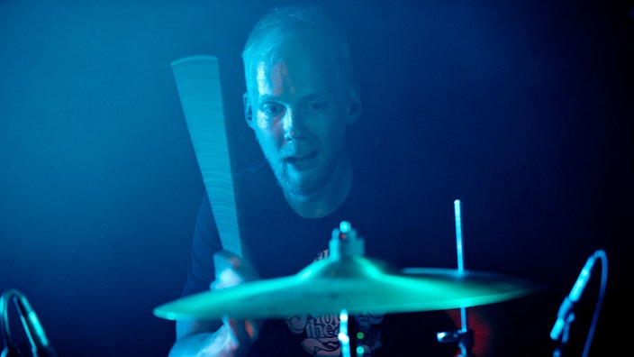 Der Drummer von Breton schlägt erfreut auf sein Drumkit ein.