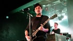 Der Gitarrist der Band spielt mit geschlossenen Augen auf seiner schwarzen Gibson Les-Paul Gitarre.