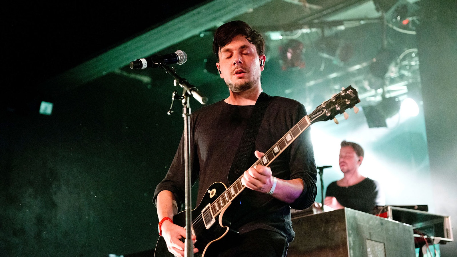 Der Gitarrist der Band spielt mit geschlossenen Augen auf seiner schwarzen Gibson Les-Paul Gitarre.