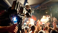 Im Vordergrund ist eine der Filkameras des Rockpalast zu sehen während im Hintergrund die Menge die Band abfeiert.