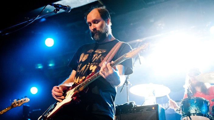 Doug Martsch an der Gitarre. Er trägt - wie alle seine Bandkollegen auch - ein einfaches T-Shirt.