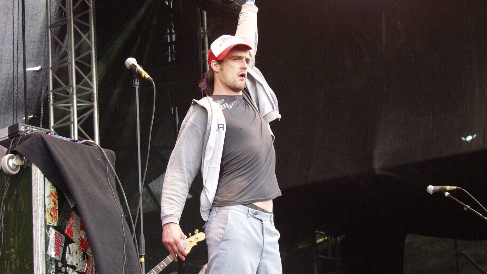 Winson mit Gitarre in der rechten Hand, zeigt mit der linken Hand nach oben.