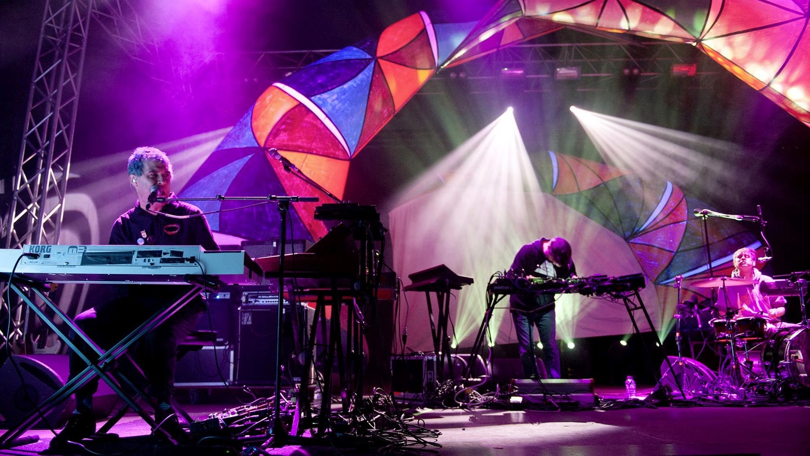 Die Band "Animal Collective" unter bunten Lichtbögen auf der Bühne.
