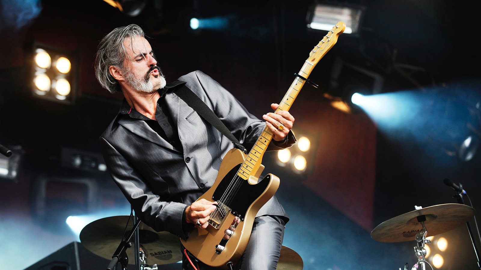 Ein Gitarrist beugt sich schräg nach links und spielt dabei Gitarre