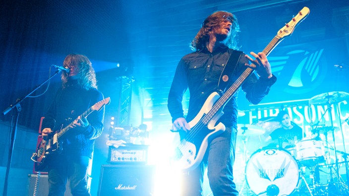 Gitarrist und Bassist der Band "Hathors" im blauen Bühnenlicht nebeneinander