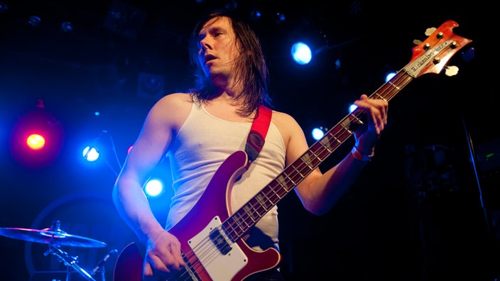 Der ebenfalls langhaarige Allan Stewart spielt  im Unterhemd Bass.