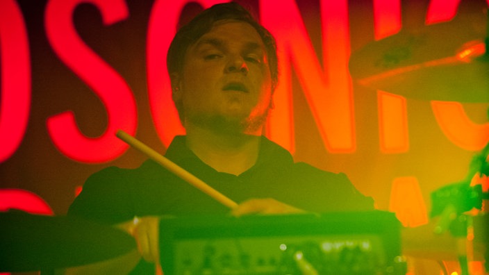 Drummer von Iris, der hinter seinem Drumkit hervorblickt.