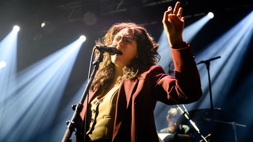 Singer-Songwriterin Mina Richman singt in ein Mikrofon. 