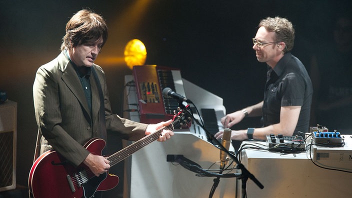 Der zweite Gitarrist und der Keyboarder stehen zusammen auf der Bühne.