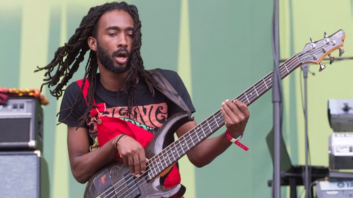 Der Bassist ist ganz in sein Siel vertieft: seine Rastazöpfe schwingen umher und er sieht ein wenig entrückt aus.