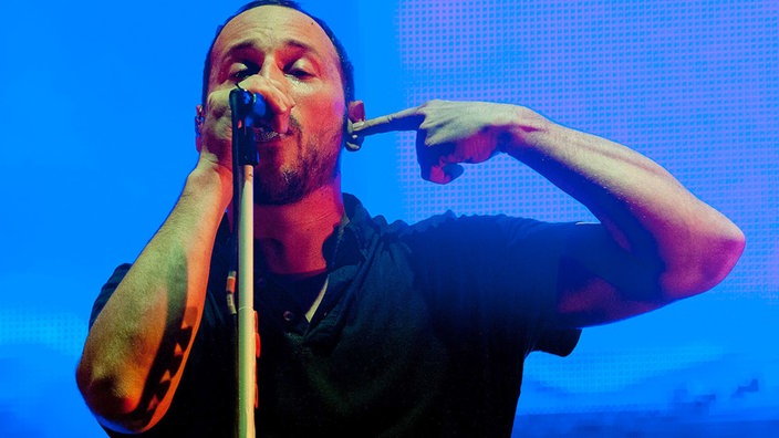 Sänger der Beatsteaks singt in sein Mikrofon und zeigt mit seiner rechten Zeigefinger auf sich