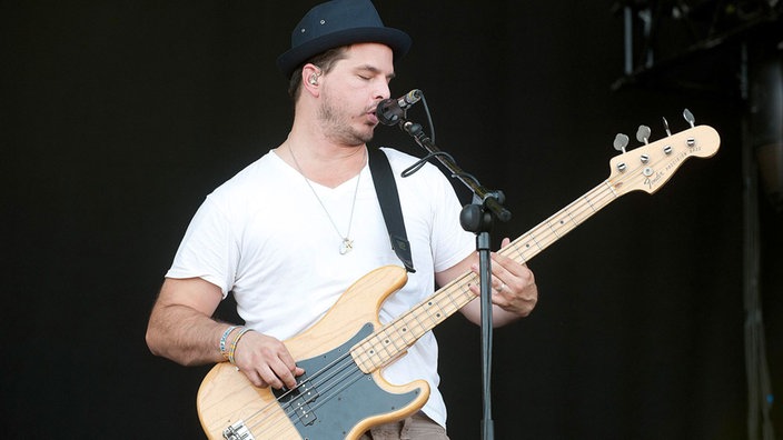 Bassist von Disptach trägt einen Hut und spielt ein H auf seinem Fender Precision Bass und singt ins Mikrofon