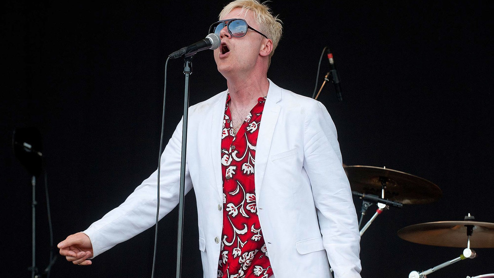 Sänger der Me First & The Gimme Gimmes singt ein lautes O ins Mikrofon, hat ein schönes weißes Jacket und ein Hawaii-Hemd an
