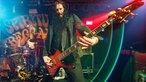 Bassist der Spiritual Beggars spielt im buten Bühnenlicht.